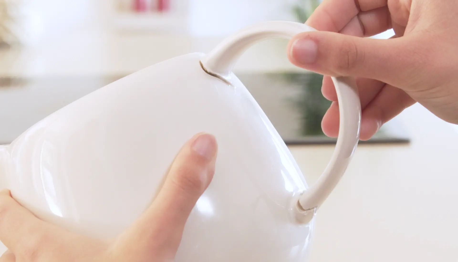 primer plano de la mano pegando un asa a una taza blanca